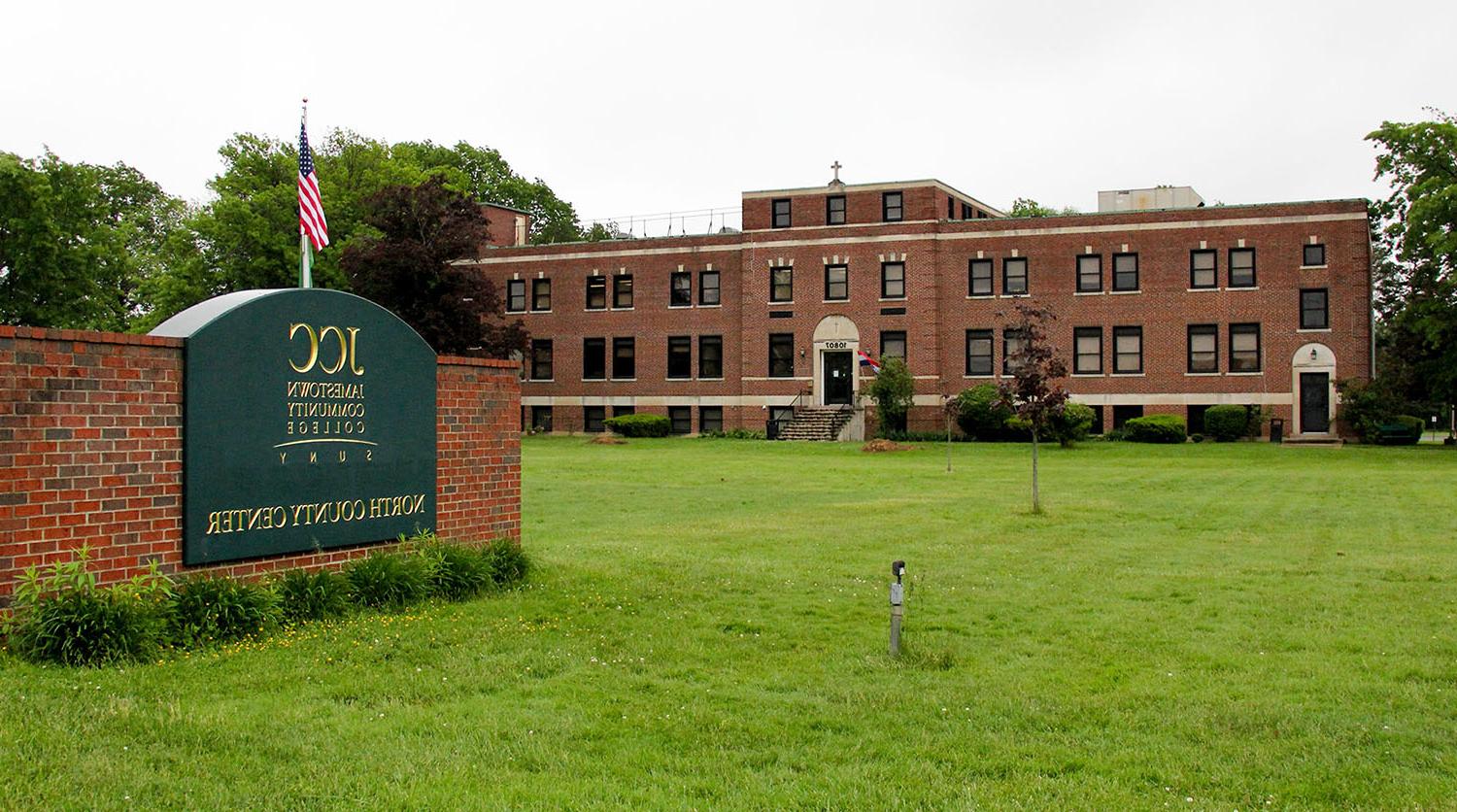 North County Center Main Building, surrounded by green lawn, with the green NCC sign with gold lettering in front of the building